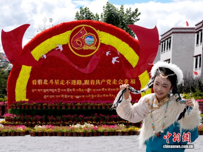 8月19日，隨著西藏自治區(qū)成立60周年慶?；顒优R近，拉薩氛圍濃。拉薩街頭，處處是張燈結彩的盛景，洋溢著一派祥和與歡騰的氛圍。圖為游客在拉薩大昭寺廣場上的大慶宣傳標語前留念。<a target='_blank' href='/'>中新社</a>記者 李林 攝